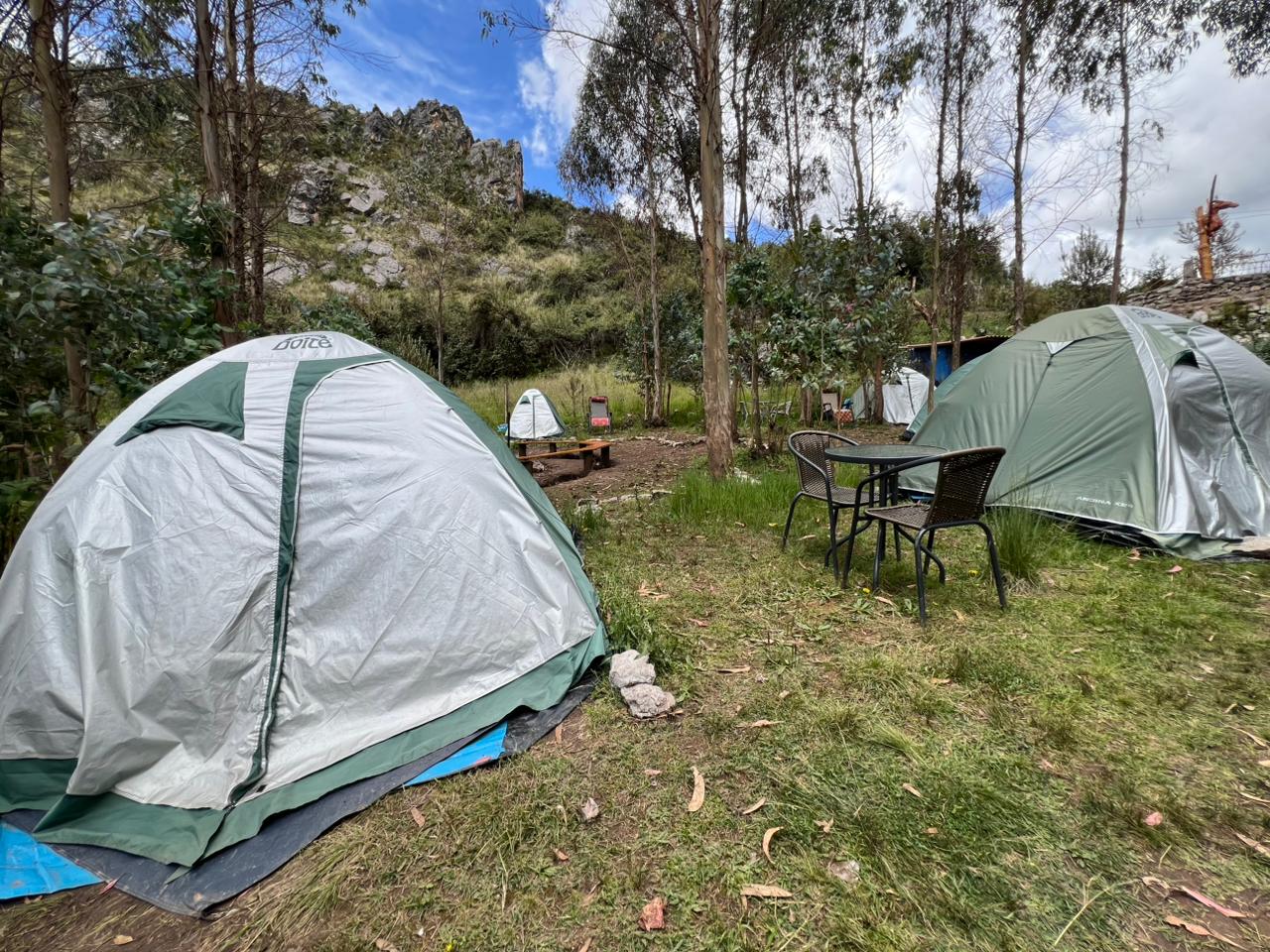 Camping en las montañas con tienda y fogata nocturna